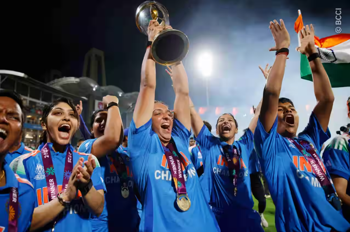 Harmanpreet kaur with its team lifting a world cup trophy and celebrating it.