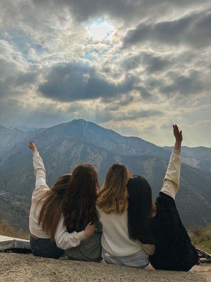 Group of four friends sitting together on mountains