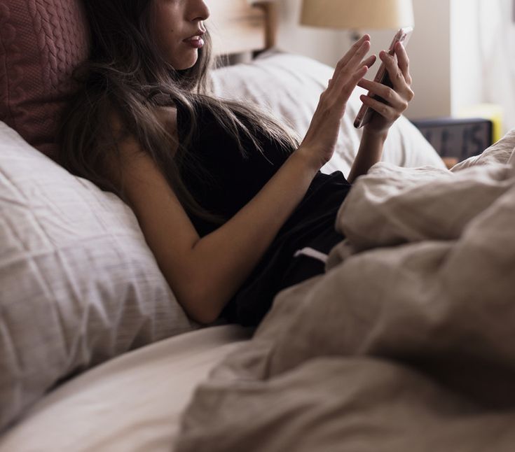 A girl looking at her phone in bed