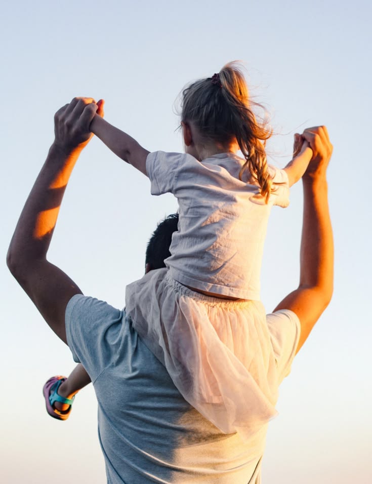 A daughter rides on her father's shoulders.
